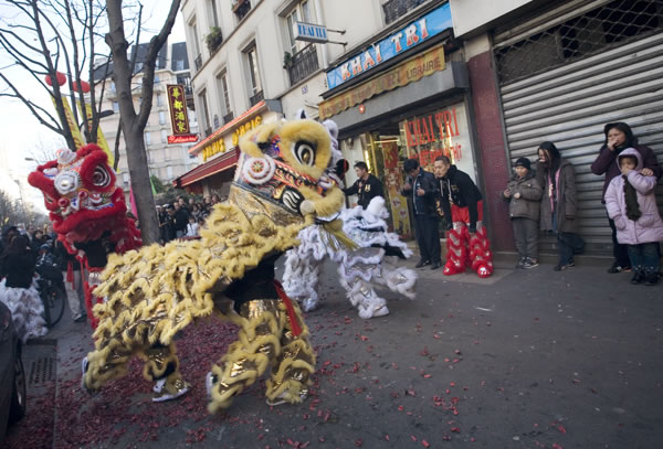 post-fireworks-dragon-dance A lion dance troupe performs in front of a shop in the “quartier chinois” in Paris. As part of the Chinese New Year celebration, after the firecrackers are set off, the lions do their dance. They go door to door, where invited, to offer this symbolic ritual to welcome the Lunar New Year and chase out any bad spirits from the premises. Photo by Danielle Voirin.